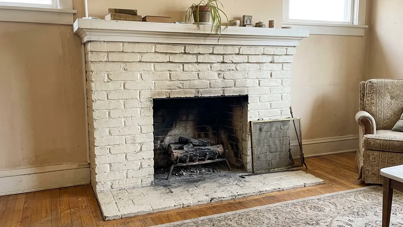 Before: a living room fireplace with a dated painted brick fireplace with a plain white mantel